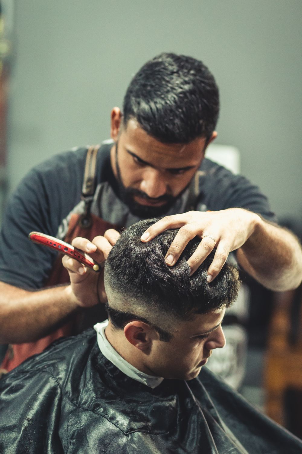 Tukang cukur merapikan potongan rambut dengan sisir